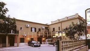 A building with a beige facade, multiple windows, and a car parked in front. - Le Rose (Tivoli)