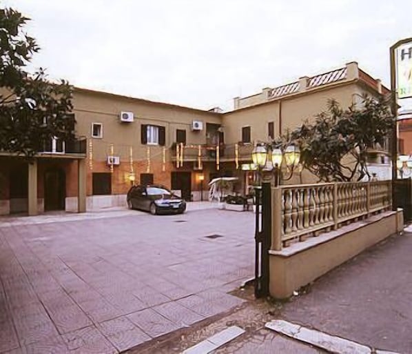 Um edifício com fachada bege, várias janelas e um carro estacionado em frente.