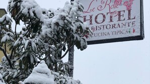 A snow-covered street with a sign for "Le Rose Hotel Restaurante Cucina Tipica". - Le Rose (Tivoli)