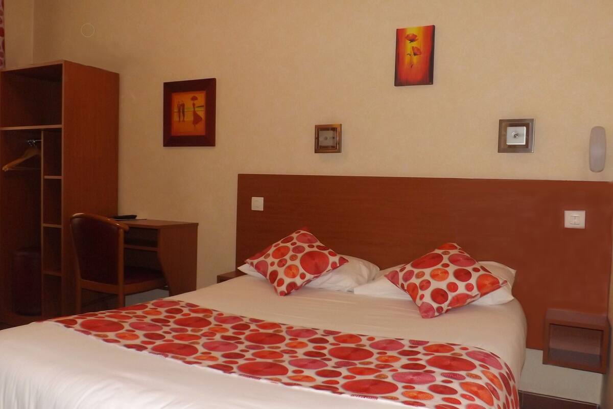 Una habitación de hotel con cama, escritorio y armario.