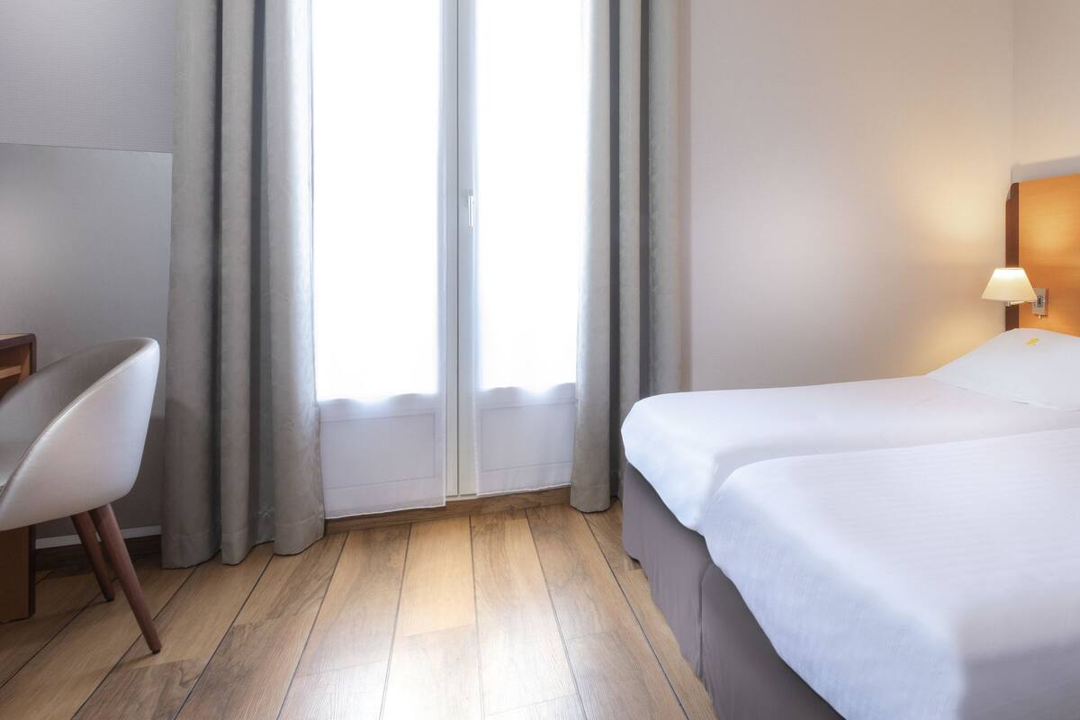 Hotellihuone, jossa on sänky, työpöytä ja tuoli.