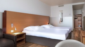 A hotel room with a large bed, bedside tables, a chair, a wardrobe, and a mirror. - Hôtel du Lion (Paris)