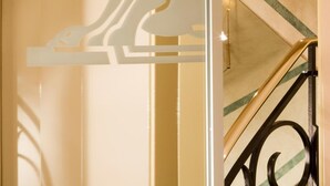 A modern interior with a minimalist design, featuring a staircase with a black railing and a wall-mounted light fixture. - Hôtel du Lion (Paris)