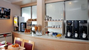 A breakfast bar with coffee machines, a refrigerator, and various food items. - Hôtel du Lion (Paris)