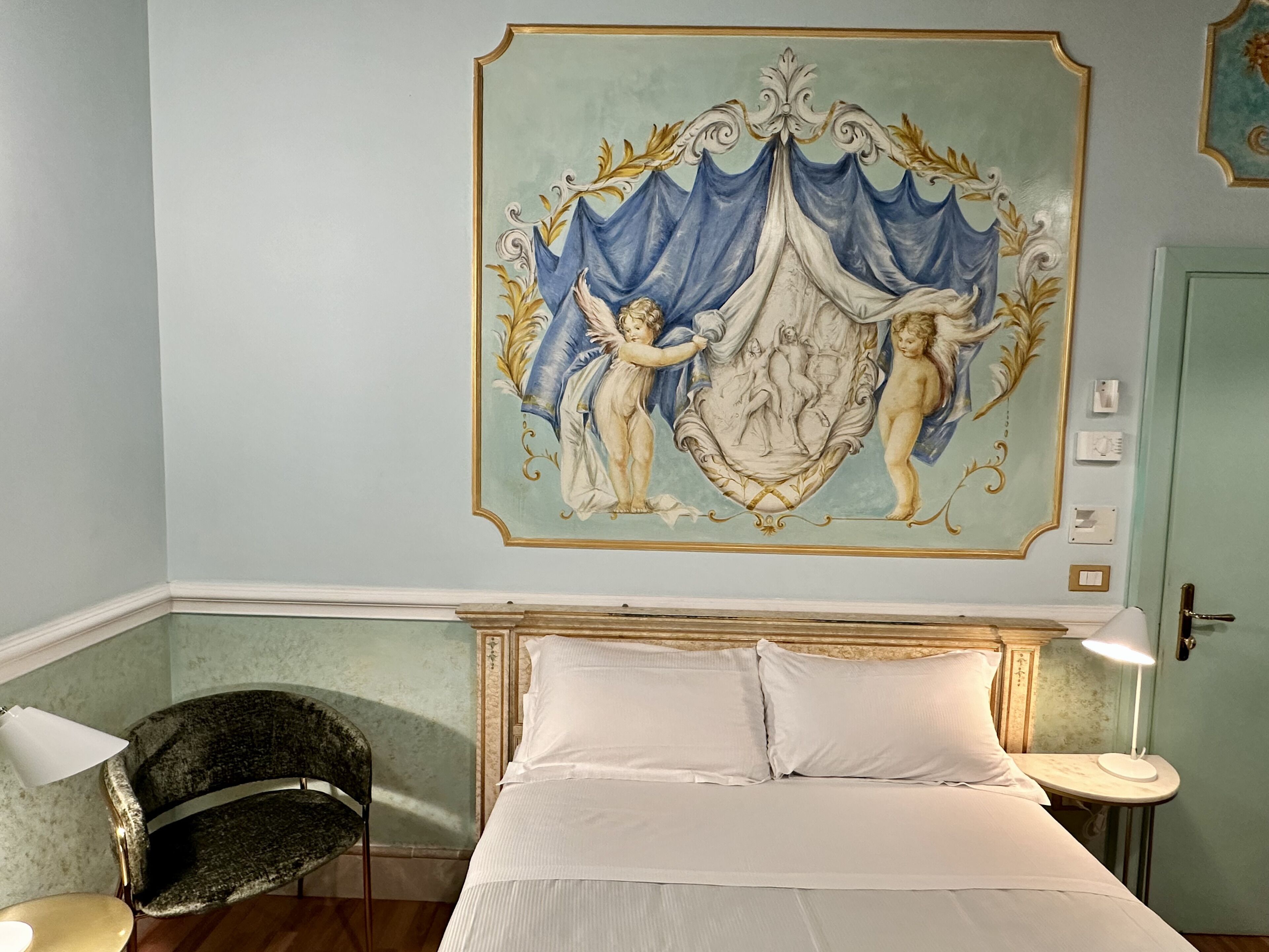 A bedroom with a bed, a chair, a nightstand, and a wall mural.