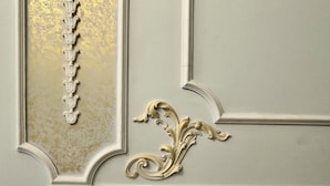 Close-up de uma parede com molduras decorativas e detalhes dourados.
