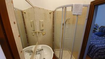 Een badkamer met een wastafel, spiegel en douche.