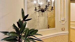 Uma sala de jantar com mesa de madeira, planta em vaso, espelho fixado na parede e lustre.
