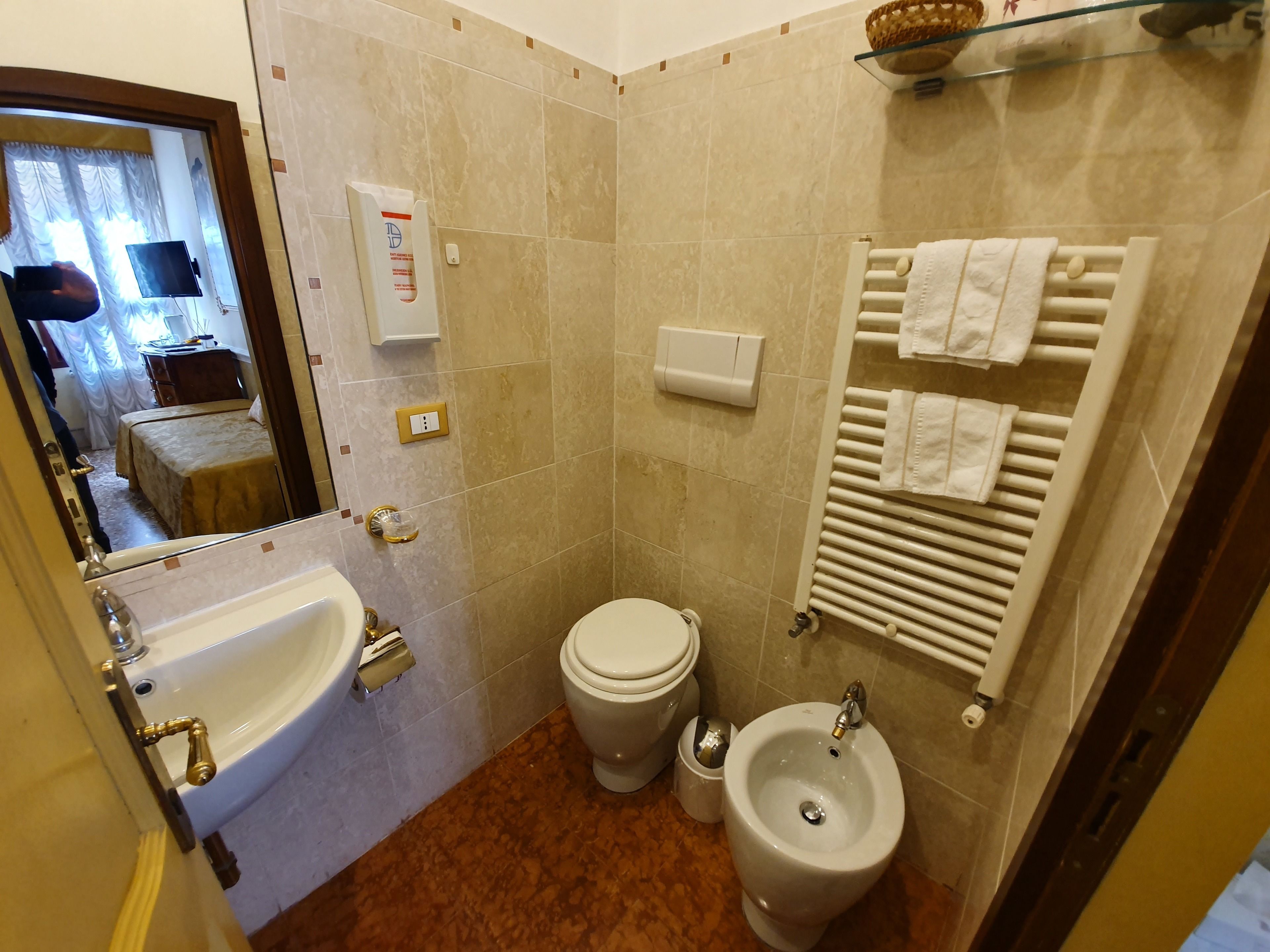 Ein Badezimmer mit Waschbecken, Toilette, Bidet und Handtuchhalter.