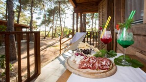 Une terrasse en bois avec une table en bois dressée pour un repas, entourée d’arbres.