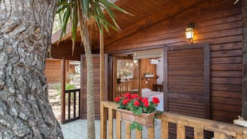 Una baita di legno con un balcone, una porta in legno e una finestra con persiane.