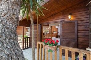 Una cabaña de madera con balcón, puerta de madera y ventana con contraventanas.