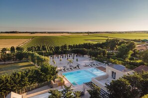 Un resort con piscina, sillas de descanso y vistas a campos de cultivo.