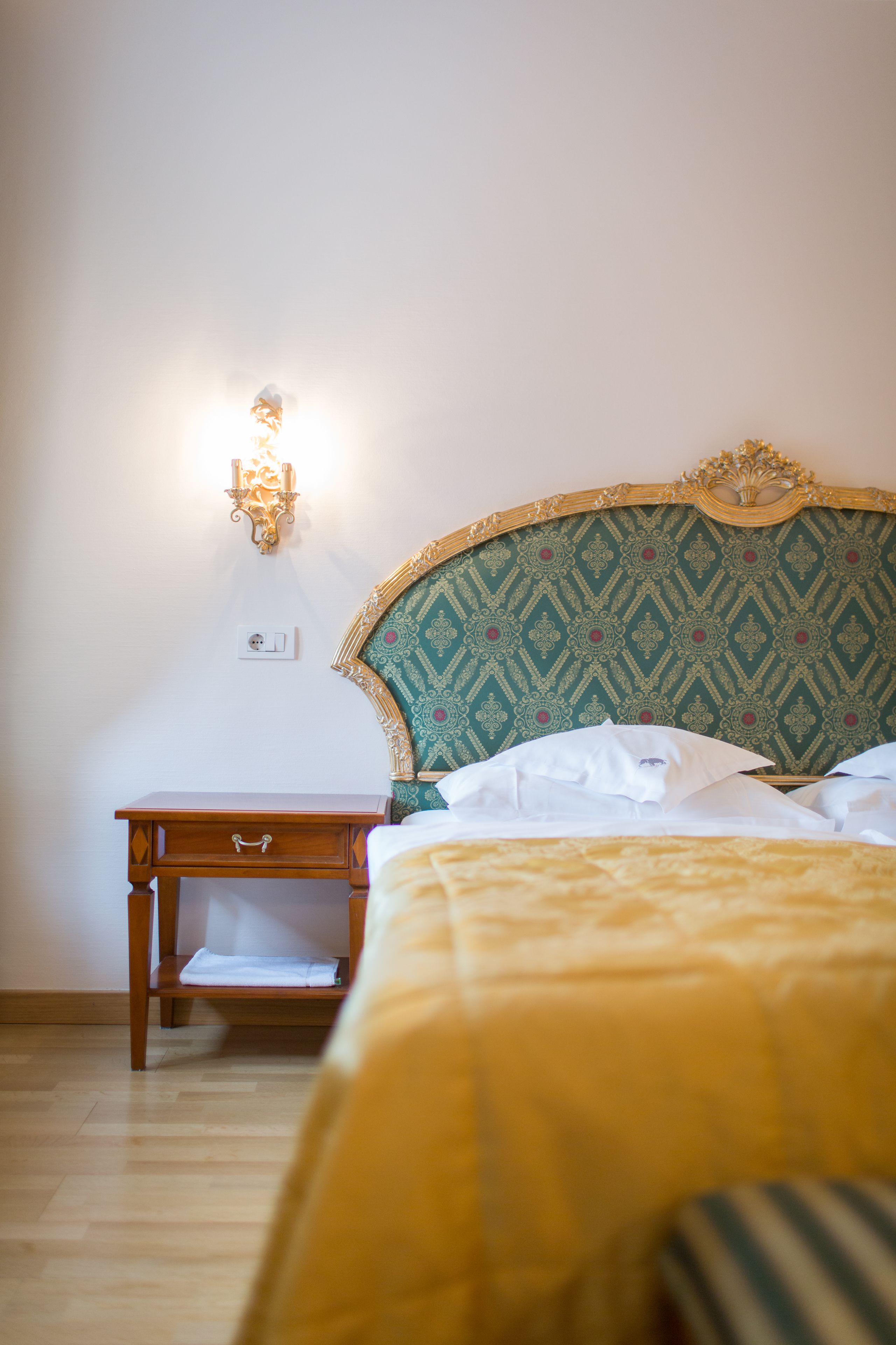 Un dormitorio con cama, mesita de noche y lámpara de pared.