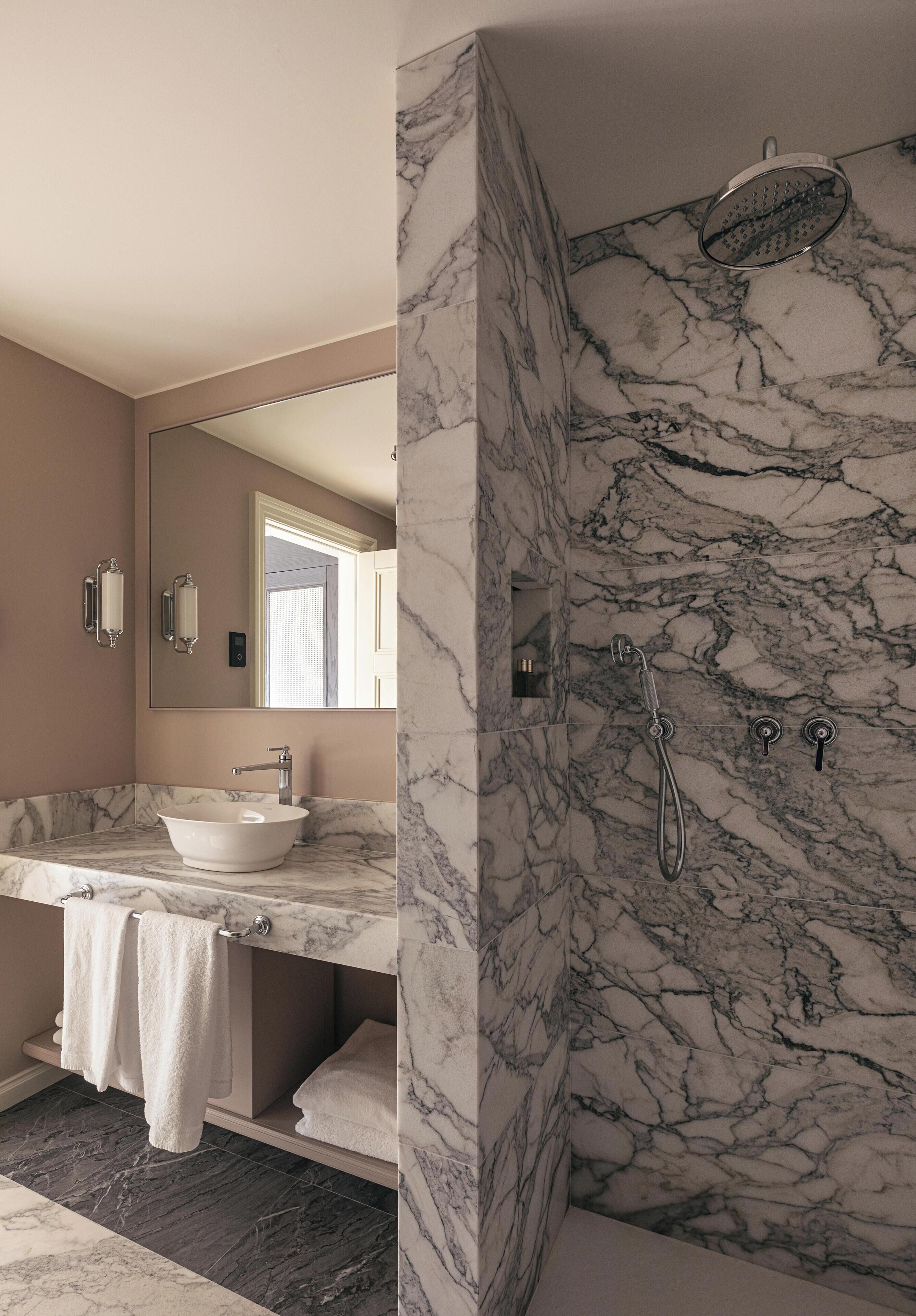A bathroom with a marble sink, a bathtub, a shower, and a large mirror.