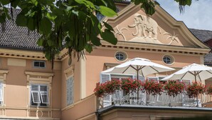 A building with a balcony featuring white umbrellas and red flowers.