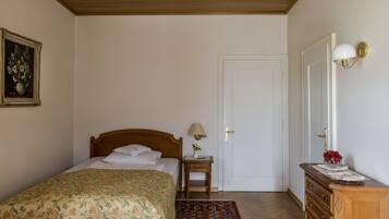 Un dormitorio con una cama de madera, una mesita de noche con lámpara, un aparador y una puerta.
