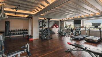A gym with various exercise equipment, a bench, and dumbbells.
