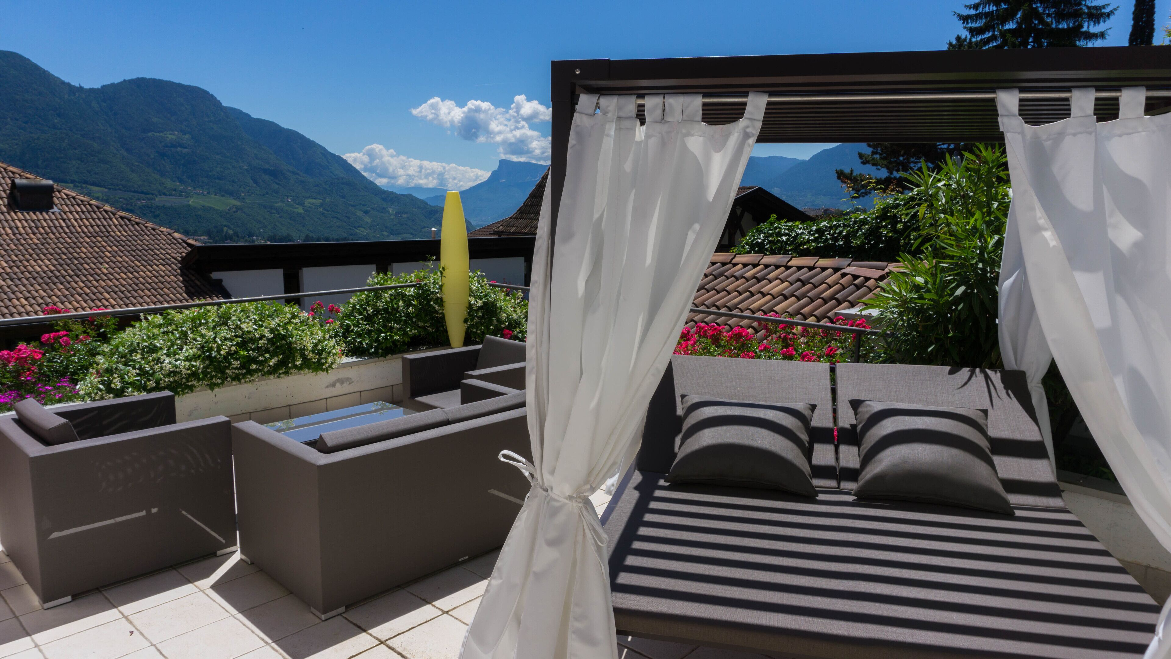 A balcony with a bed, seating area, and a view of mountains.
