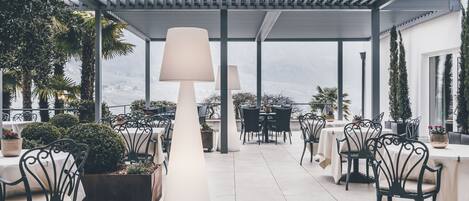 Un espace extérieur aménagé en terrasse, avec des tables et des chaises, de grandes lampes et des plantes en pot.