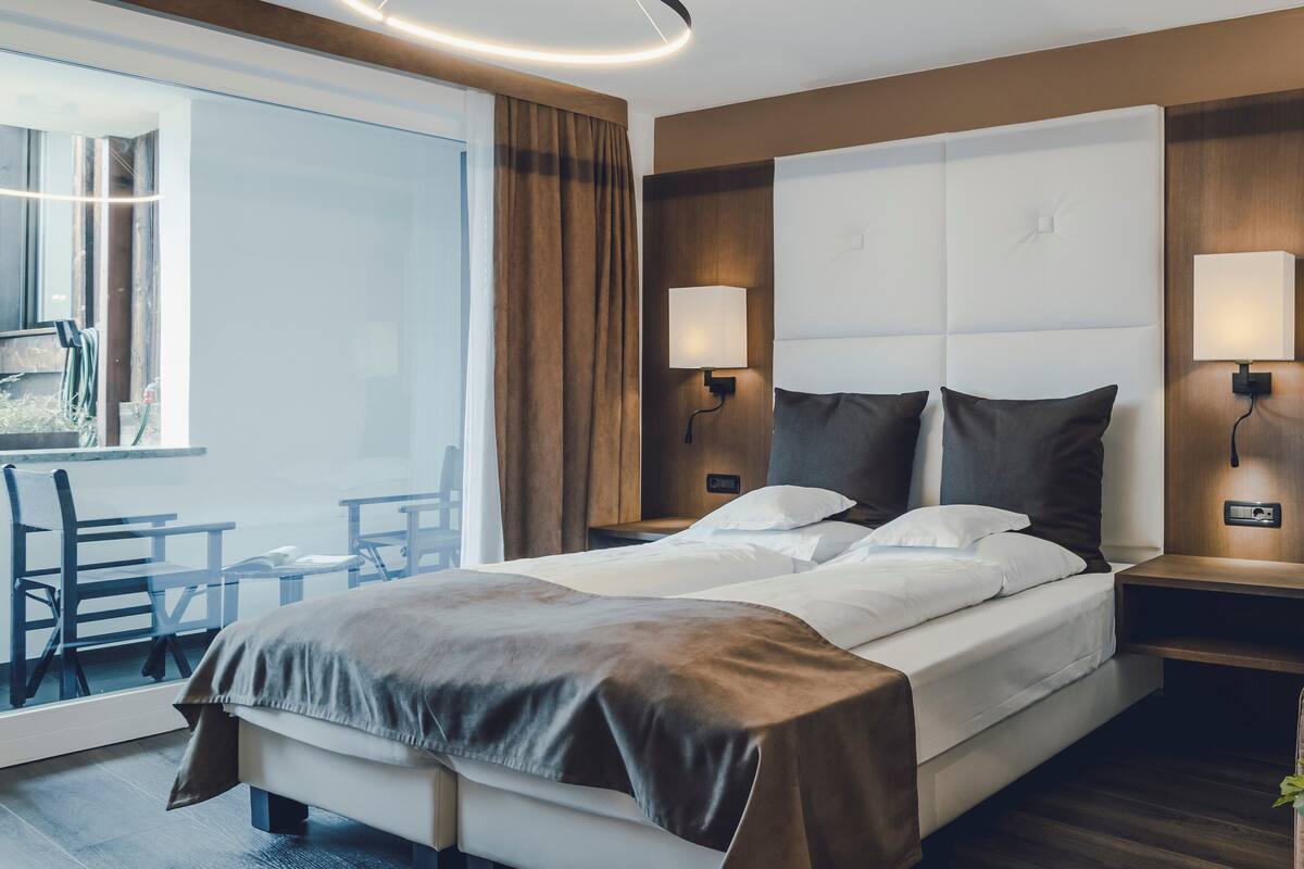 A hotel room with a large bed, two bedside tables, a desk, and a chair.
