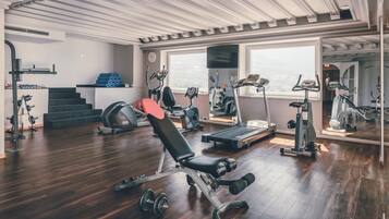 A gym with various exercise equipment, a bench, and a treadmill.