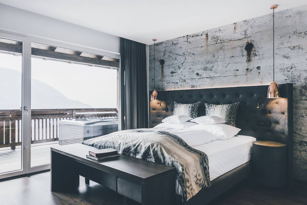 A modern bedroom with a large bed, a wooden headboard, and a view of the outdoors.