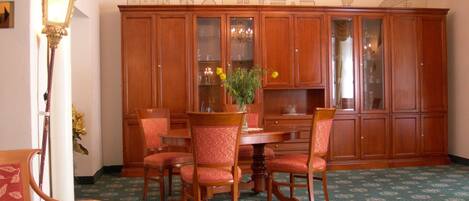 A dining area with a wooden table and chairs, a chandelier, and a cabinet with glass doors.