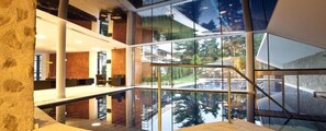 A modern interior with a glass-bottomed pool, wooden accents, and a view of greenery outside. - Hotel Residence Gasser (Bressanone)