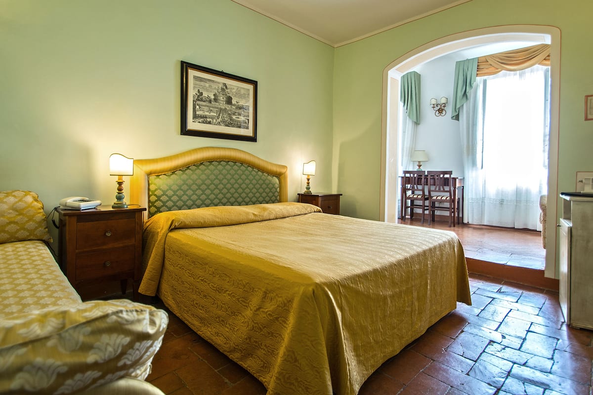 A hotel room with a bed, a nightstand, a desk, and a chair.