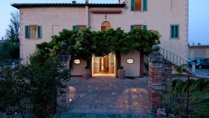 A two-story building with a central entrance, green shutters, and a brick staircase leading up to the door. - Palazzo di Valli (Siena)