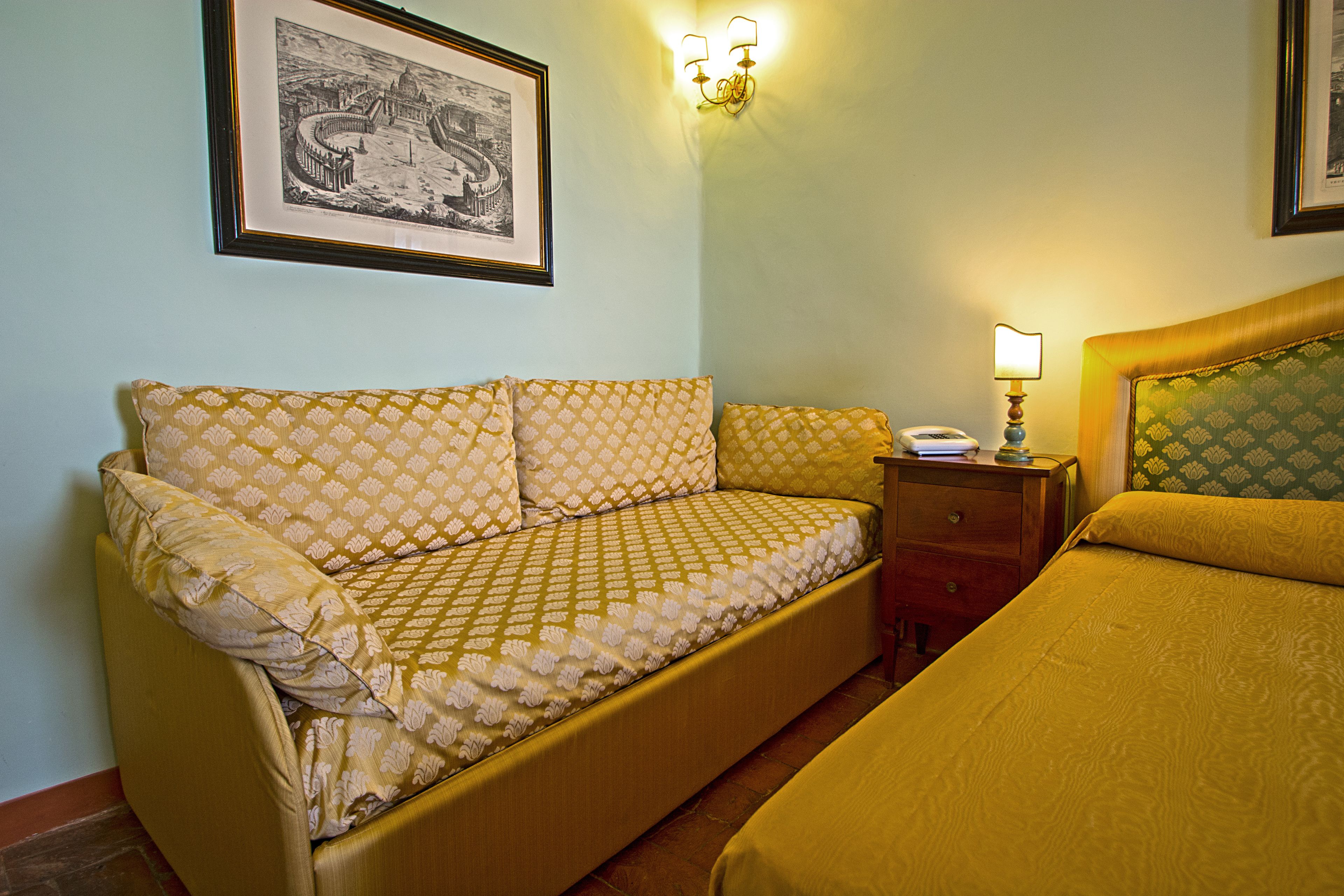 Una habitación con un sofá, una mesita de noche con lámpara y una cama.