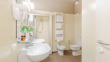 Ein Badezimmer mit zwei Waschbecken, einer Dusche, einer Toilette und einem Handtuchhalter.