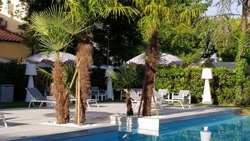 A swimming pool with palm trees and lounge chairs.