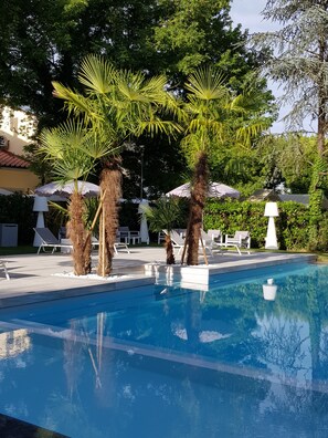 Piscina con palmeras y sillas de descanso.