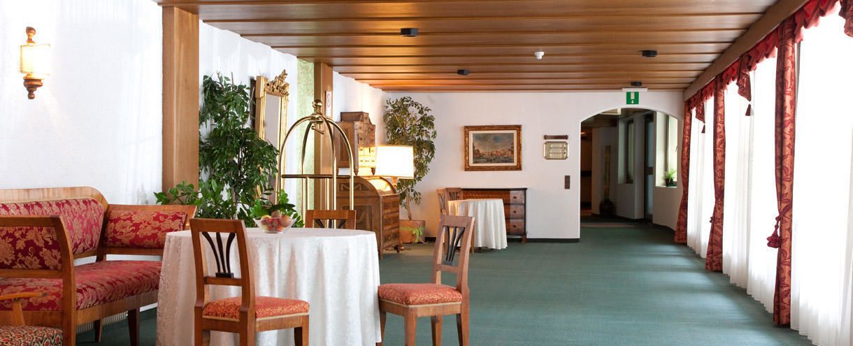 En hotellobby med trämöbler, en grön matta och en öppen spis.