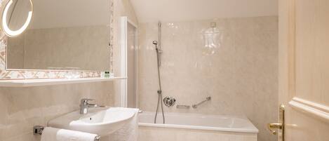 A bathroom with a sink, mirror, and bathtub.