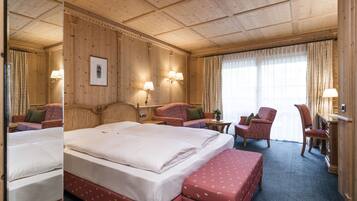 Una camera d'albergo con un letto grande, due poltrone, una scrivania e una finestra con tende.