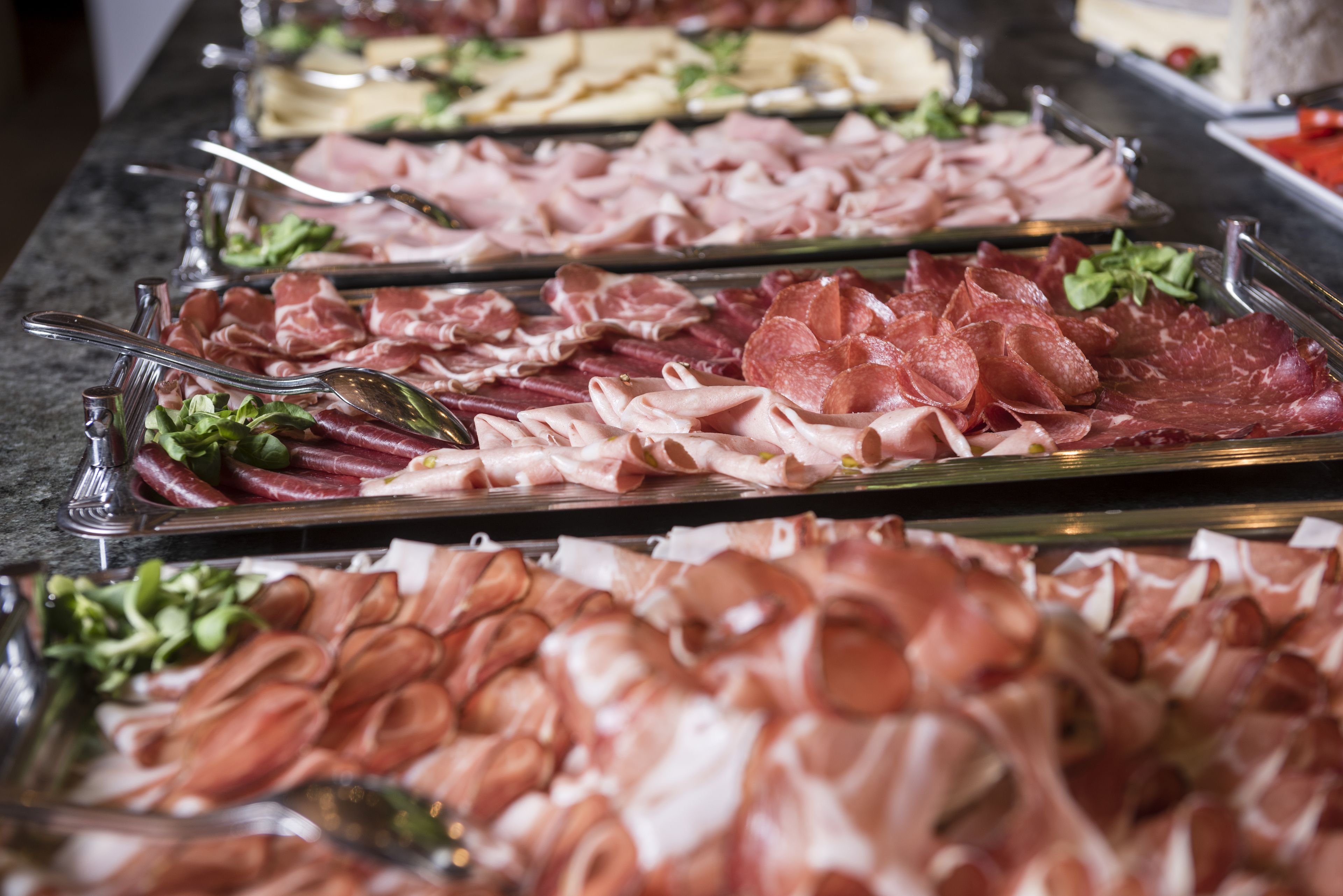 A buffet with various types of deli meats and cheeses.