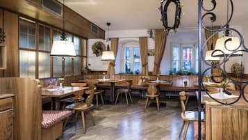 Un restaurant chaleureux, doté de meubles en bois, de grandes fenêtres et de lampes décoratives.