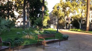 Un parque con un banco, árboles y un edificio al fondo.