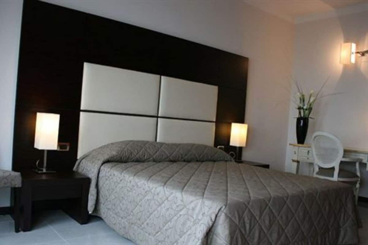 A modern bedroom with a large bed, two bedside tables, a desk, and a chair.