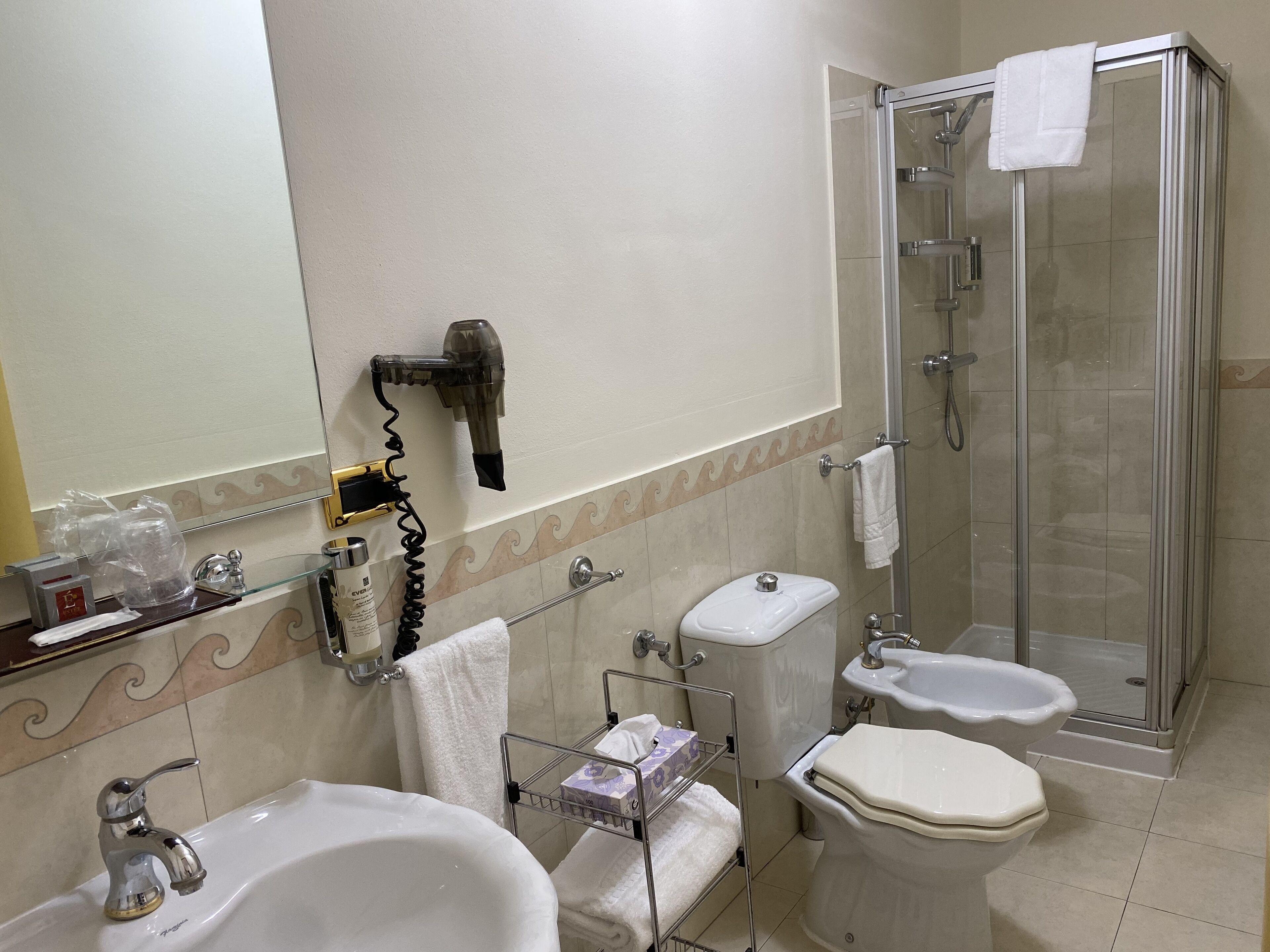 Un baño con lavamanos, inodoro, ducha y secador de pelo.