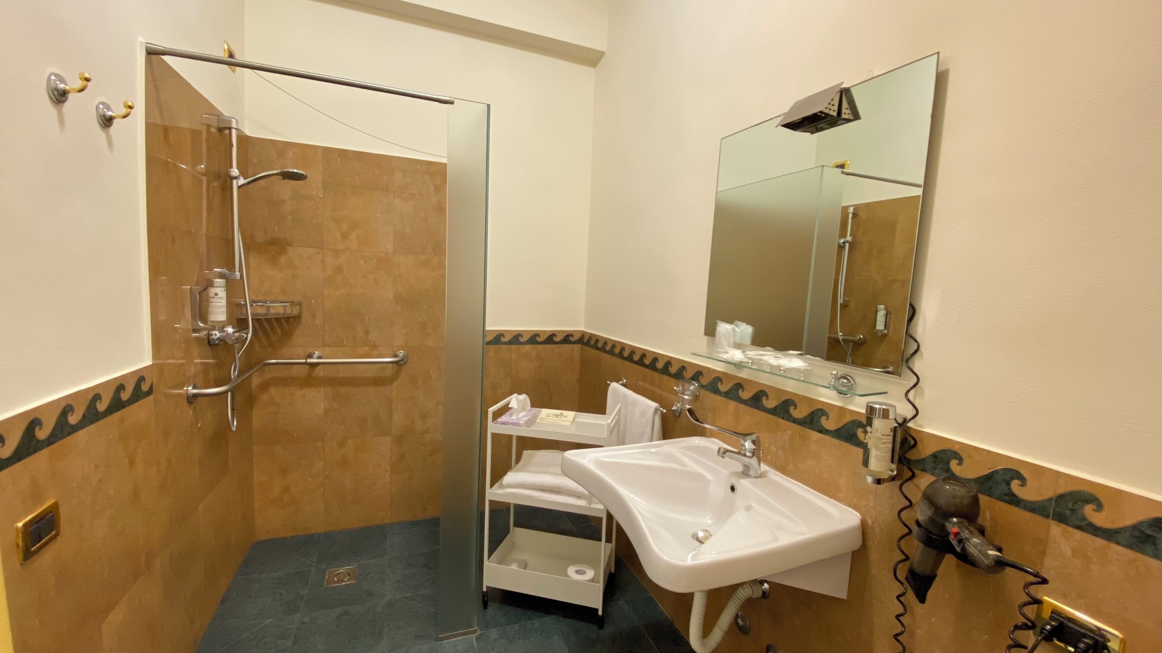 Un baño con cabina de ducha de vidrio, un lavabo, un espejo y un perchero para toallas.