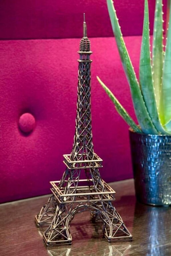 A miniature Eiffel Tower model on a wooden surface with a potted aloe vera plant in the background. - Jack's Hotel (Paris)