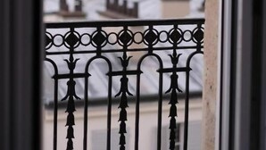 A balcony with a wrought iron railing, overlooking a cityscape with buildings and a river. - Amiral (Paris)