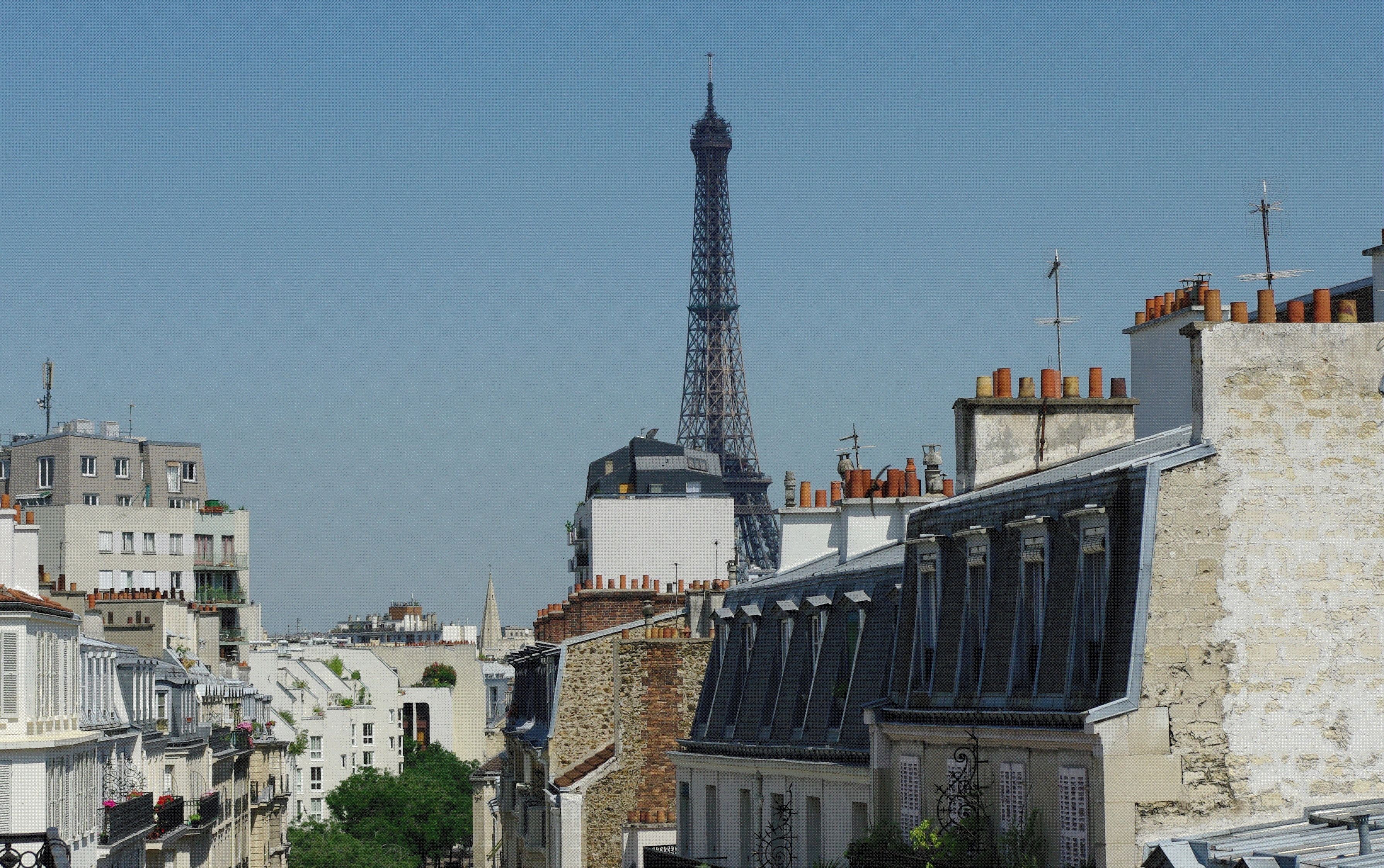 A view of the Eiffel Tower with surrounding buildings, including a mix of residential and commercial structures.