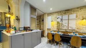 A modern kitchen with a central island, a dining area with a stone wall, and a tiled floor. - Amiral (Paris)