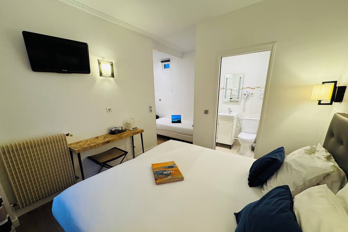 Une chambre d’hôtel équipée d’un lit, d’un bureau, d’une chaise, d’une télévision, d’un miroir, d’une salle de bain et d’un radiateur.