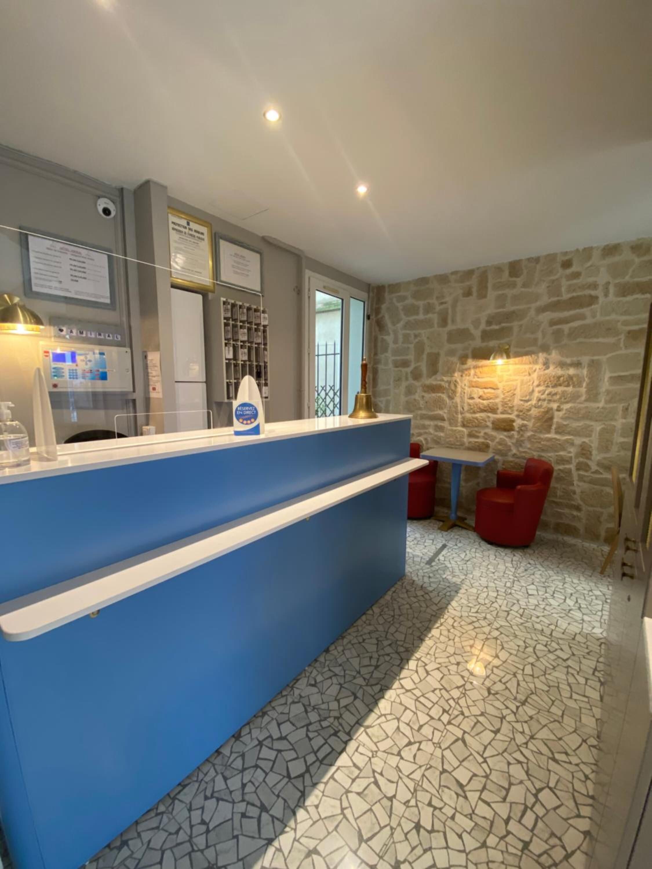 A reception area with a blue counter, a stone wall, and a tiled floor.